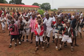 Groep leerlingen en schooltje van Kimbeimbe